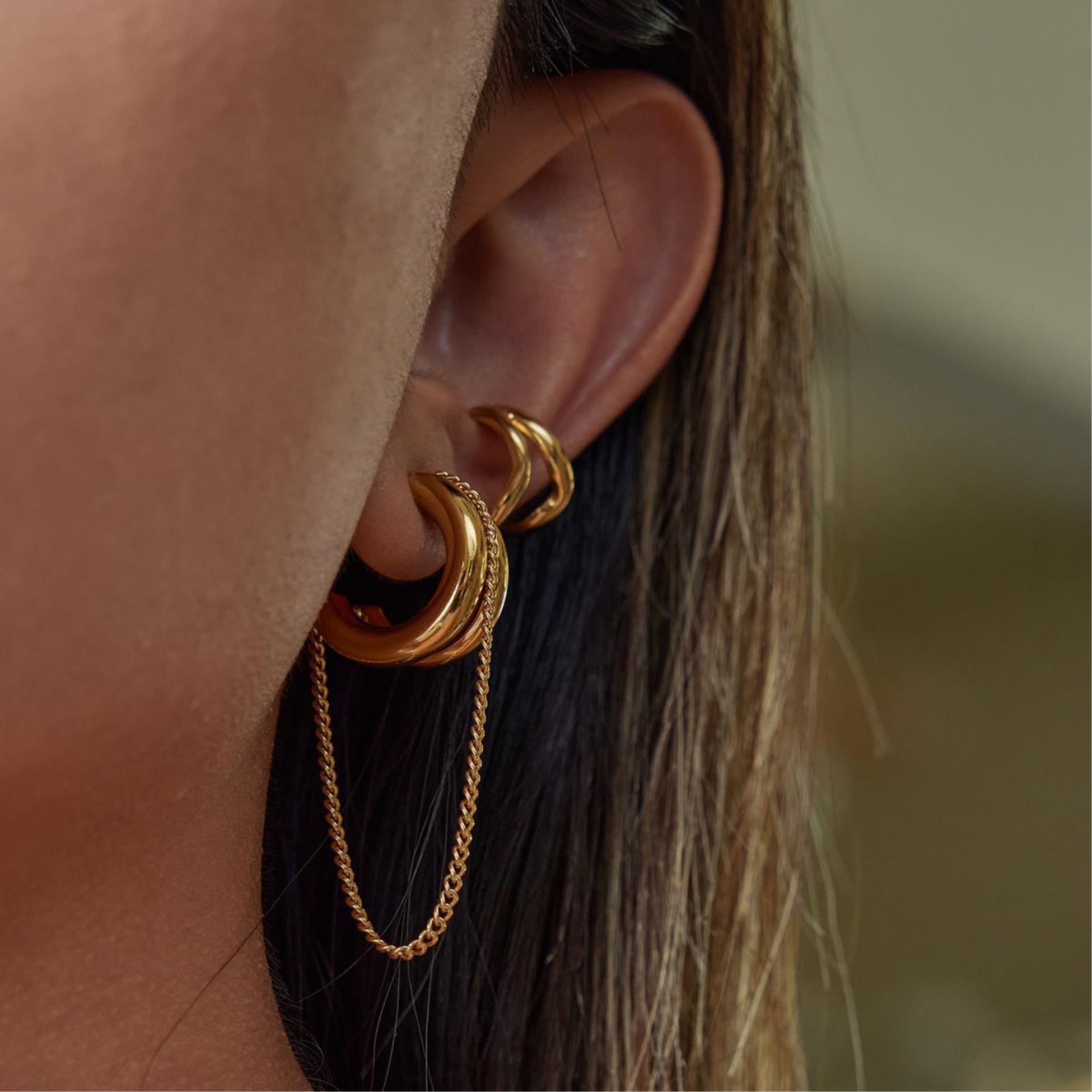 Close-up of a gold earring worn by a person with blurred background