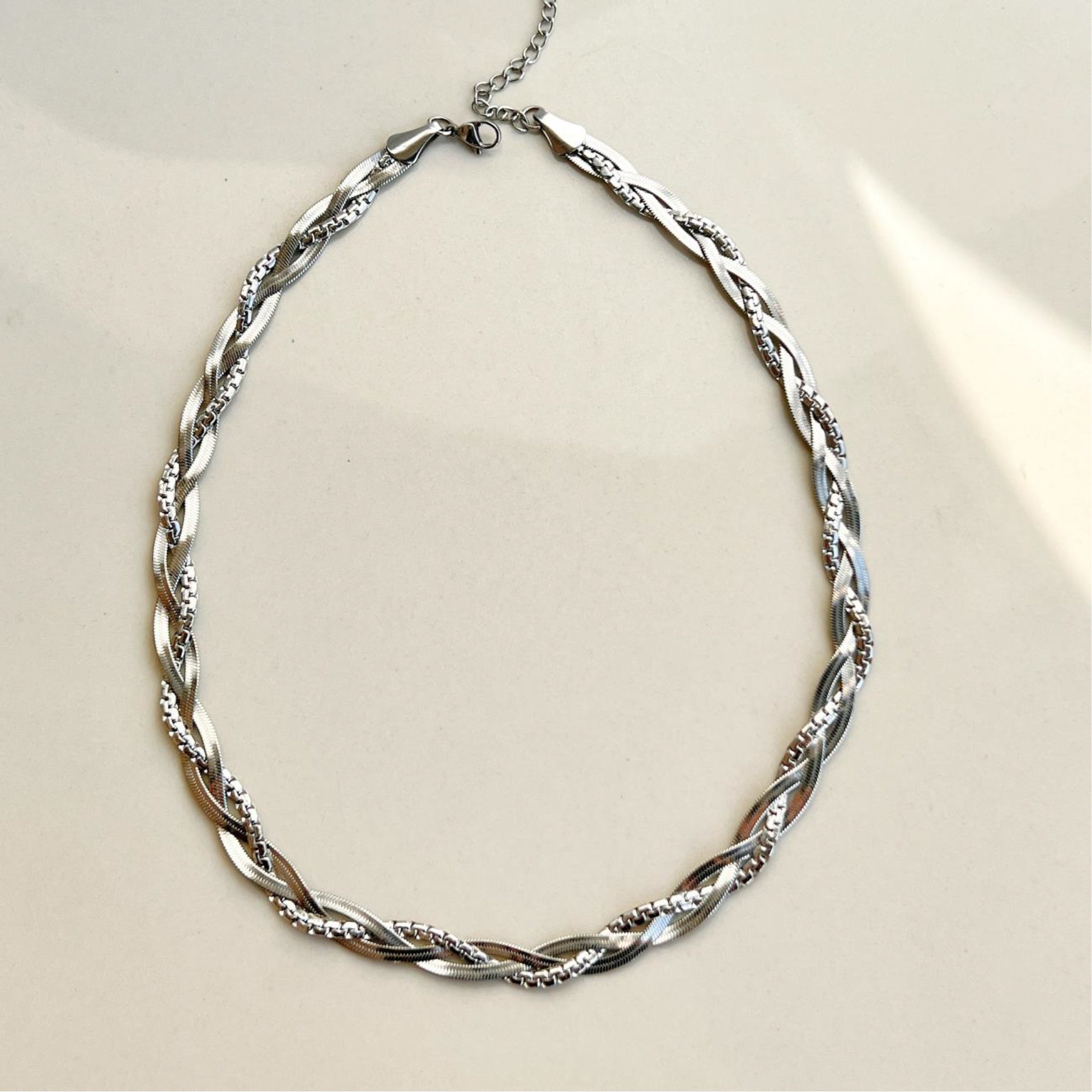Silver chain necklace on a beige background