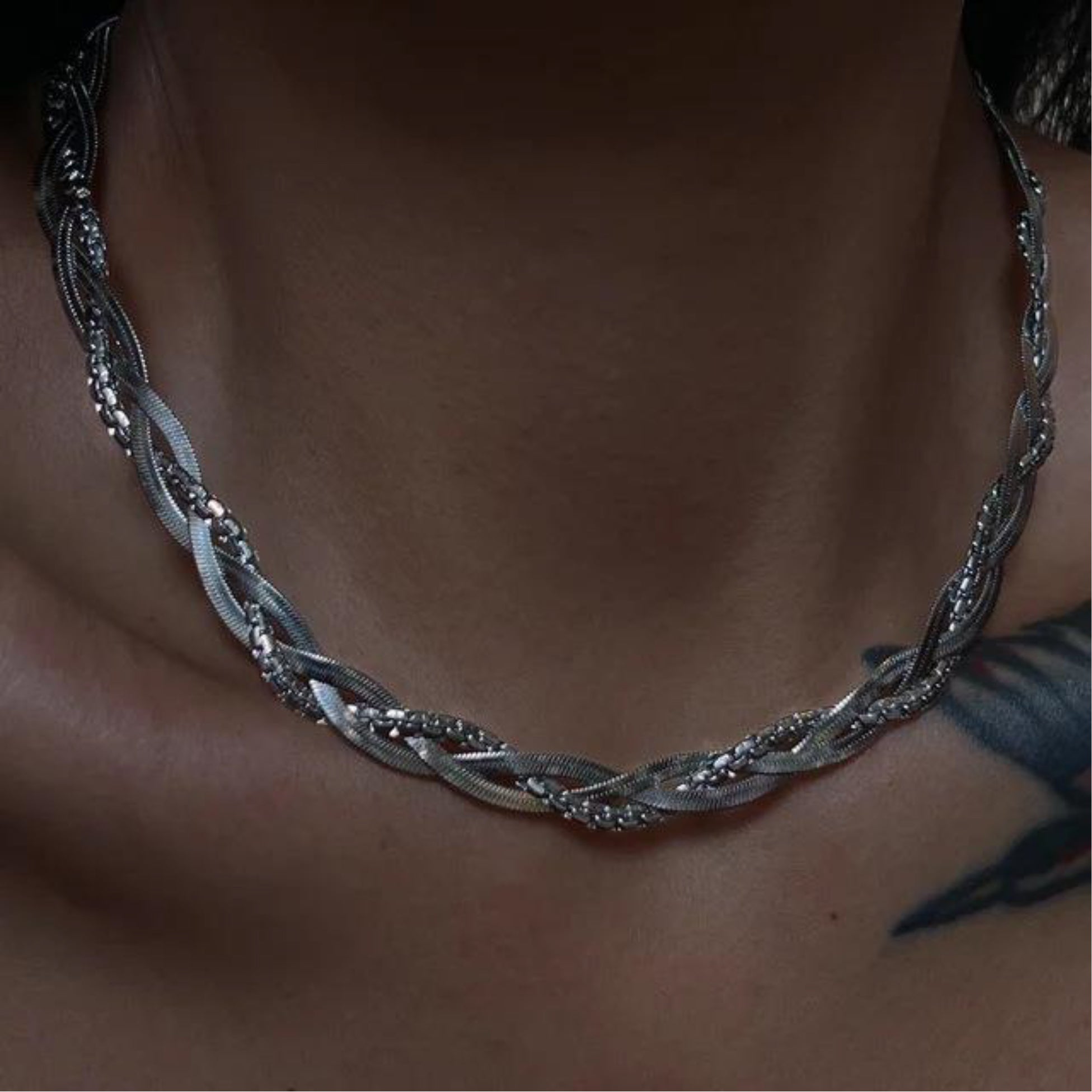 Silver braided necklace on a person's neck with a blurred background