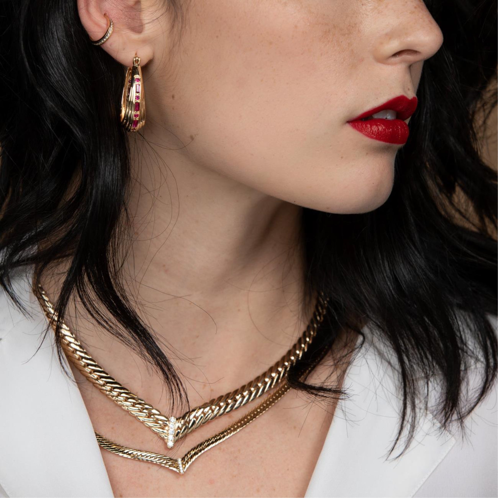 Close-up of a woman wearing gold hoop earrings and a gold necklace.