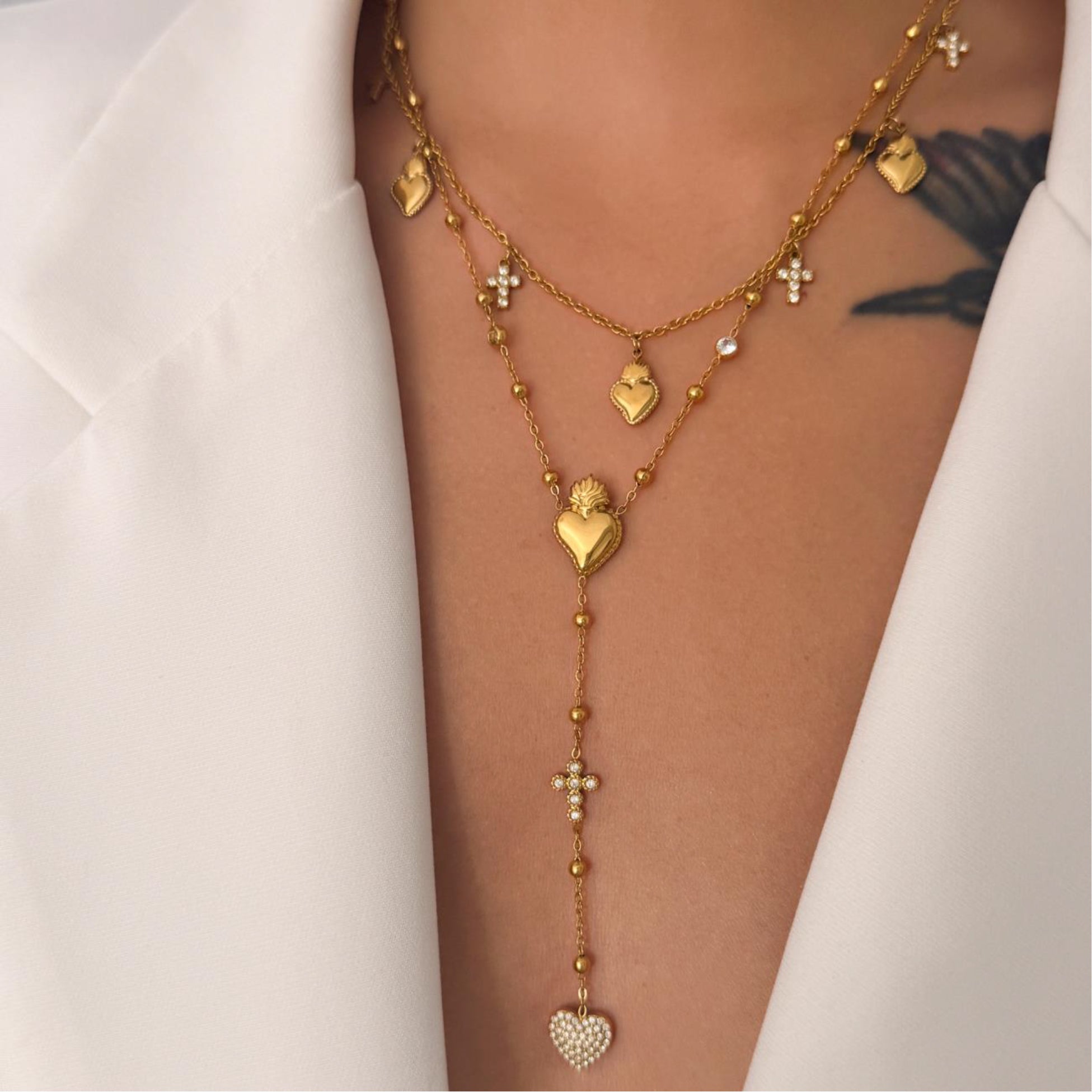 Gold heart-shaped necklace on a person's arm with a white background