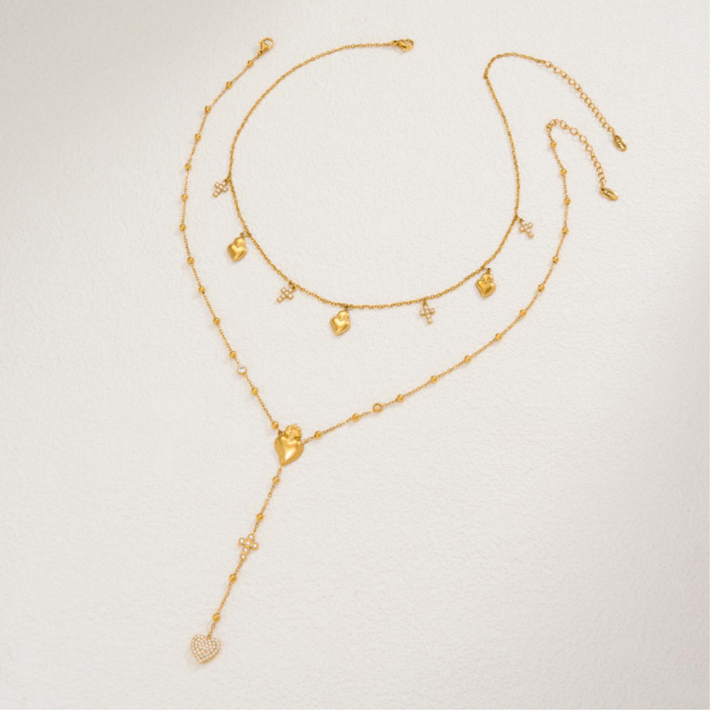 Gold necklace with heart-shaped pendants on a light gray background