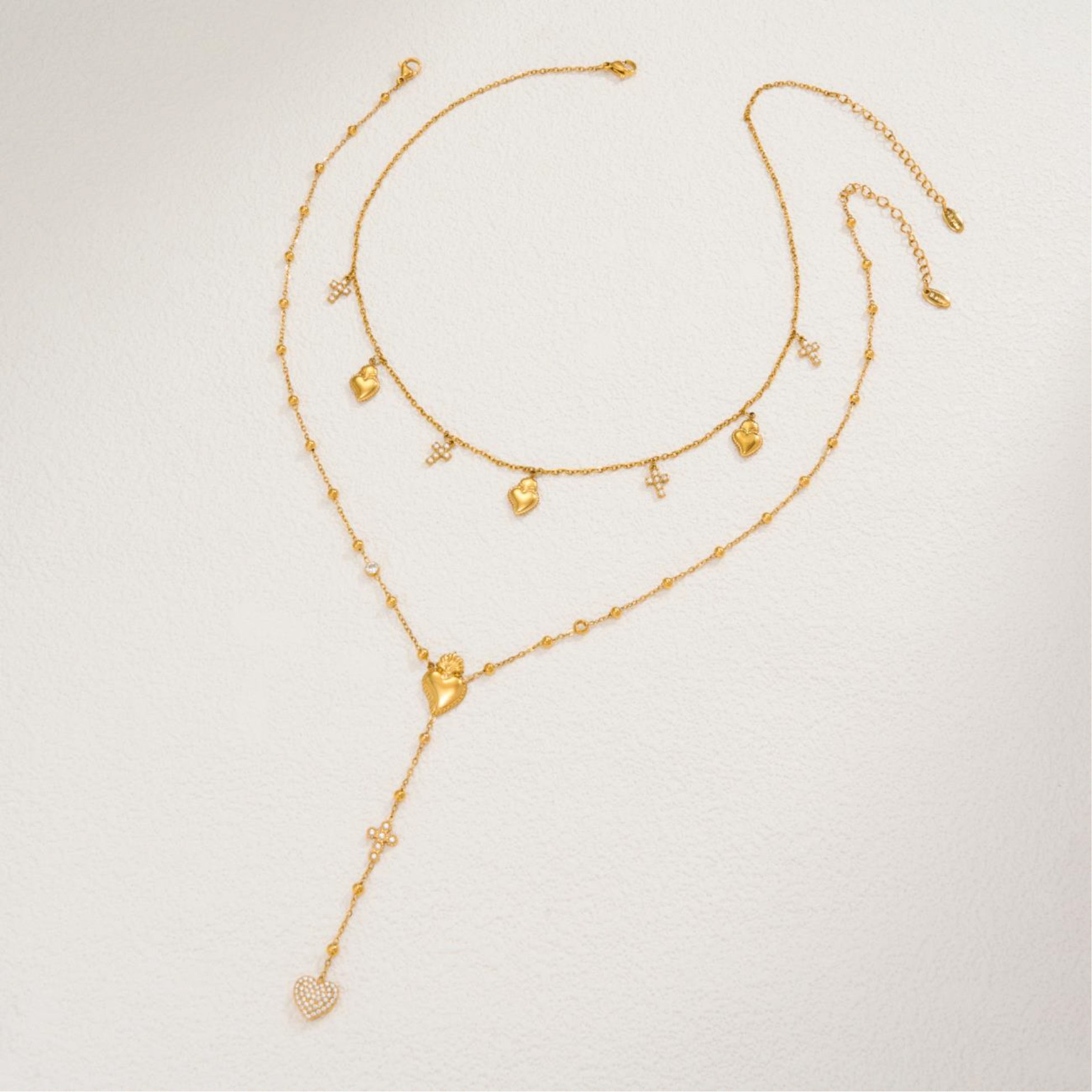 Gold necklace with heart-shaped pendants on a light gray background