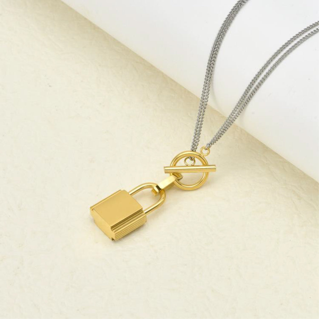 Gold lock pendant on a silver chain against a beige background